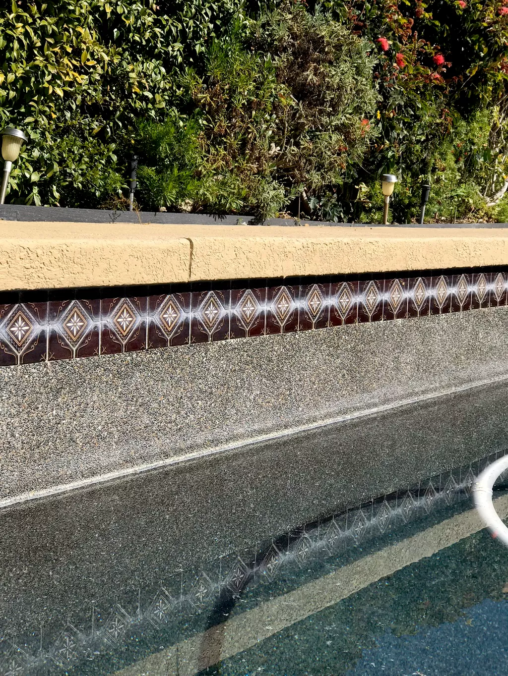Pool waterline tile with heavy calcium buildup before restoration